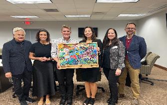 Company gathers together holding the original mural created by CVCC Visual Arts and the S.T.A.R.T. Gala participants.